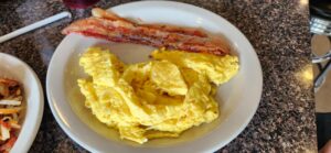 Scrambled eggs and two slices of bacon